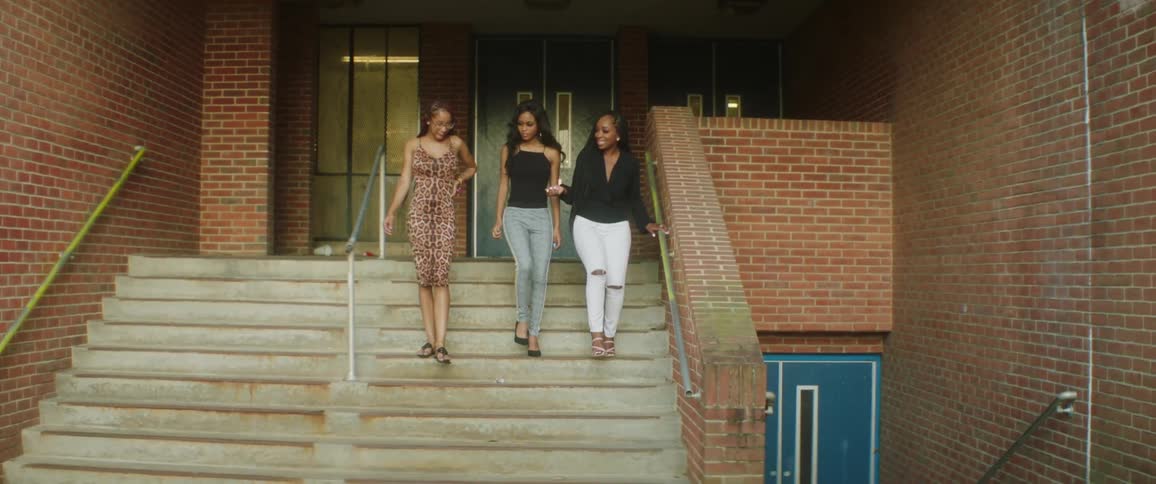 A group of femal friends talking while walking down the stairs of a building