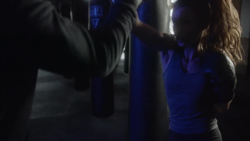 A woman throws punches as she boxes with someone
