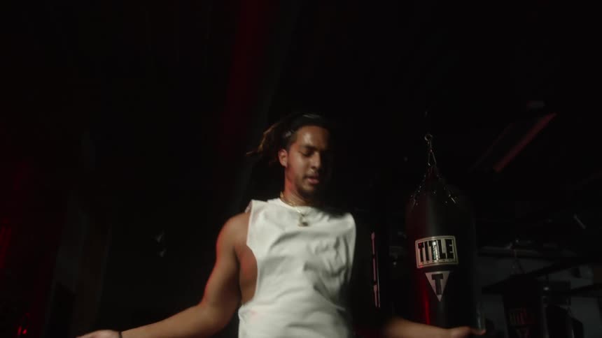 Young muscular man jumping rope inside a dimly lit gym