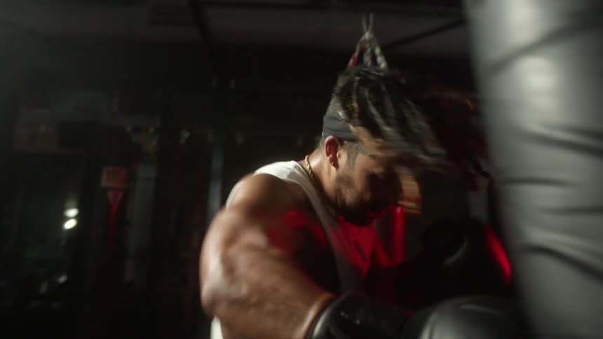 A man in a gym boxing a heavy bag with boxing gloves