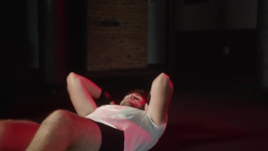 A man does sit ups and shadow punches then rests and takes a deep breath