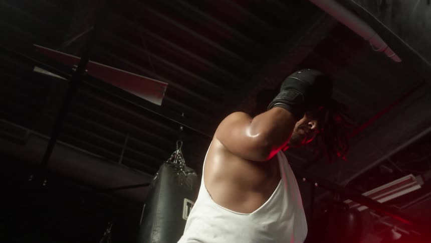 A man that is punching a punching bag in a gym