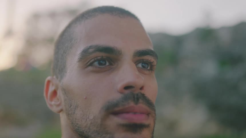 Man wipes brow breathing deeply while backed by red tinted sky