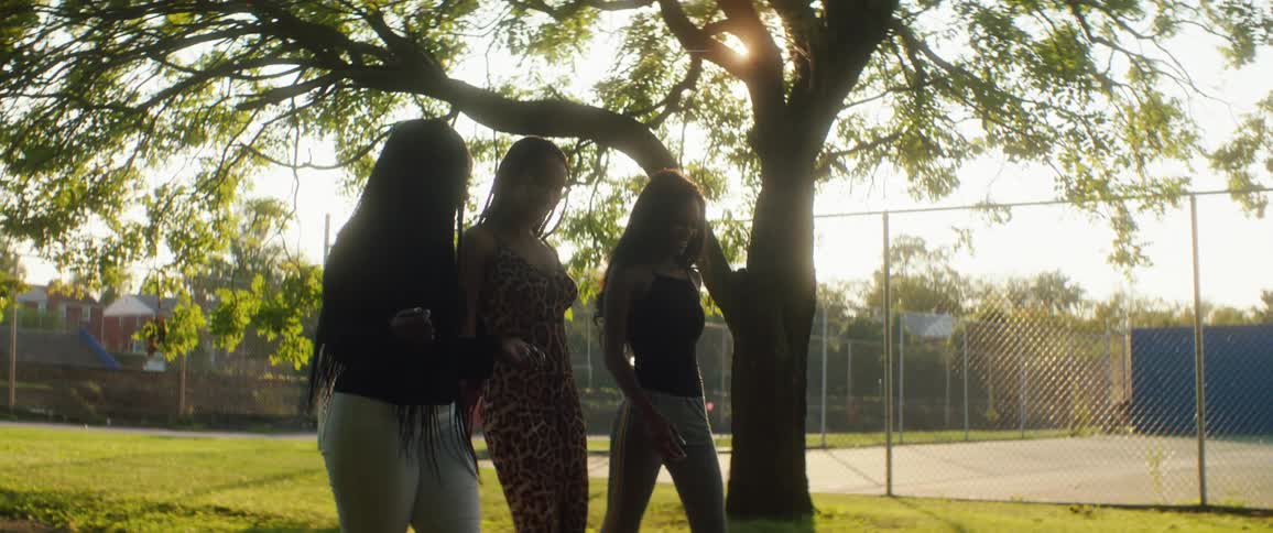 Group of female friends leisurely walking on a park at sunset