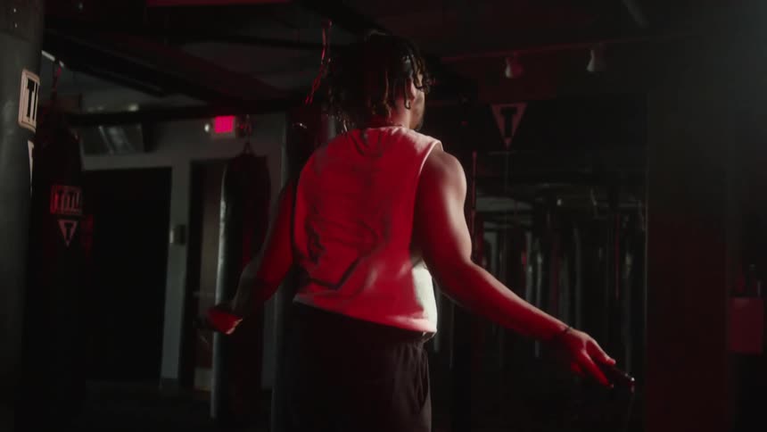 A strong fit man jumping rope inside a dimly lit gym