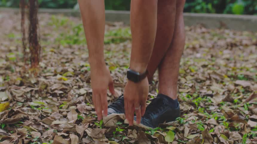 Man with smartwatch black shoes and turquoise t shirt works out in the park
