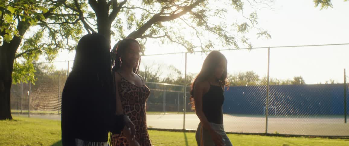 Three women walk past the tennis court