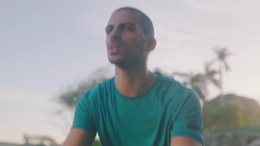 Man doing squats on a rock outdoors in a tropical area