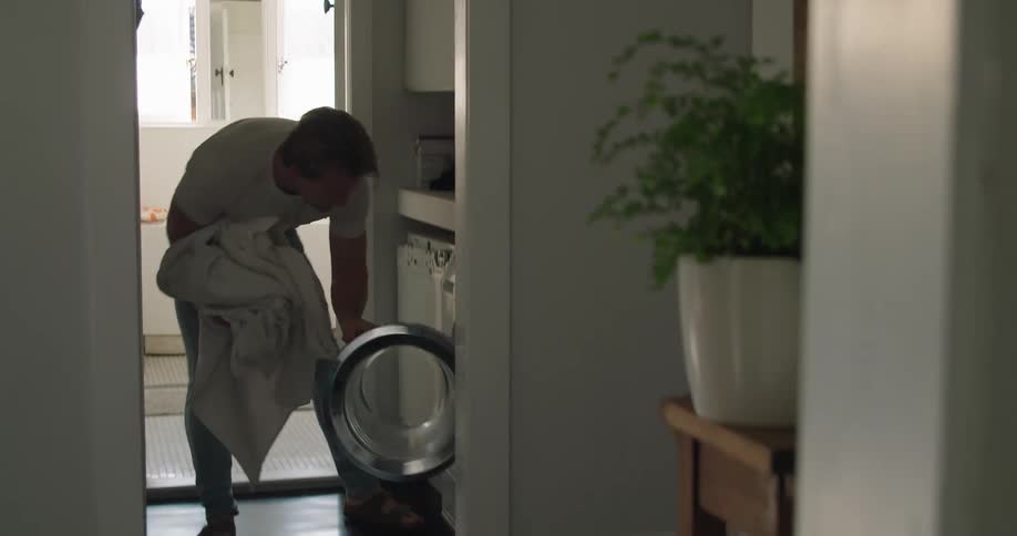 A man at home puts laundry in the washing machine