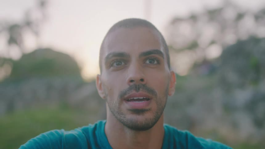 Man with short hair and stubble beard breathes fast after workout in the park
