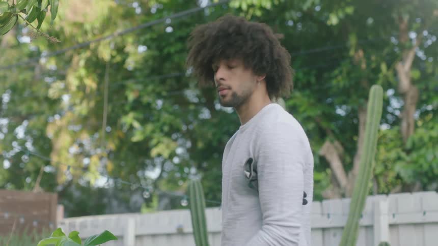 A man stands outside a home and takes gardening gloves off