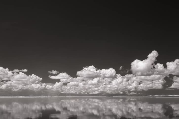 Clouds gather and roll over water which reflects the sky above on its surface