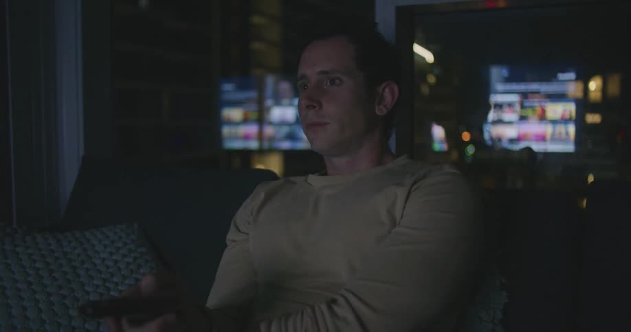 A man in a room sitting on a couch holding a remote