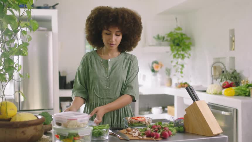 A woman in the kitchen cutting vegetables with a knife