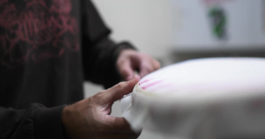 A man using tape to secure the border of a surfboard in a workshop