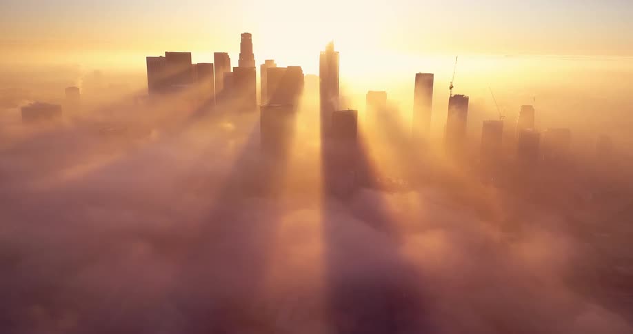 Sun shine turns heavy clouds obscuring downtown city skyline golden