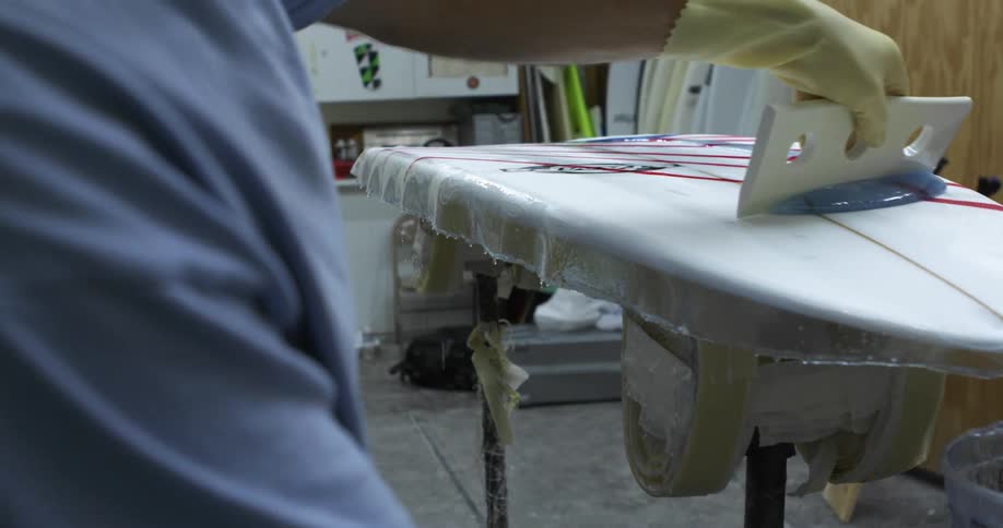 A man in a shop makes a surfboard
