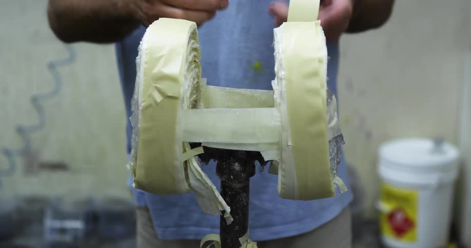 A person in a room taping up a holder with a wall and a bucket in the background