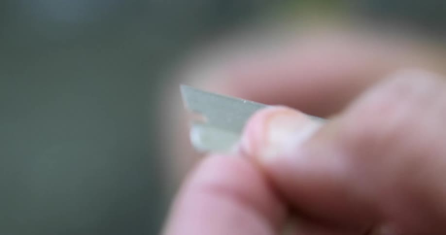 Close up of a person peeling the envelope of a razor