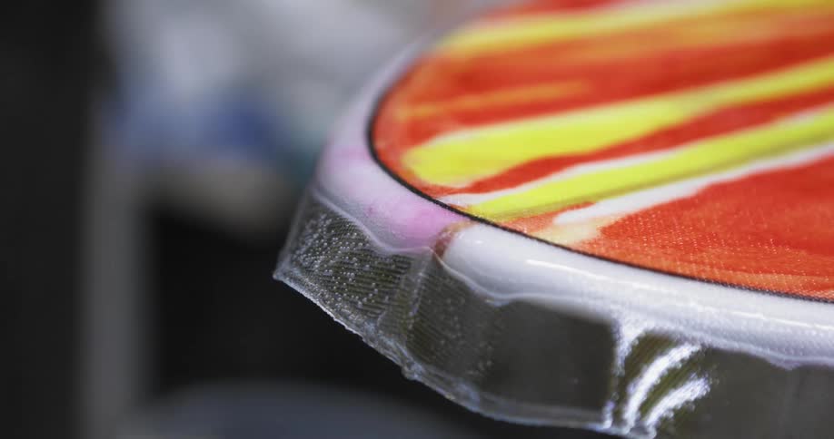 A brush is used to apply a clear coat sealer on a brightly painted surface