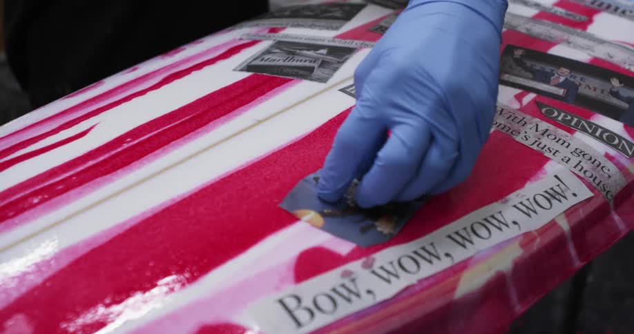 A worker putting a decal on a surfboard