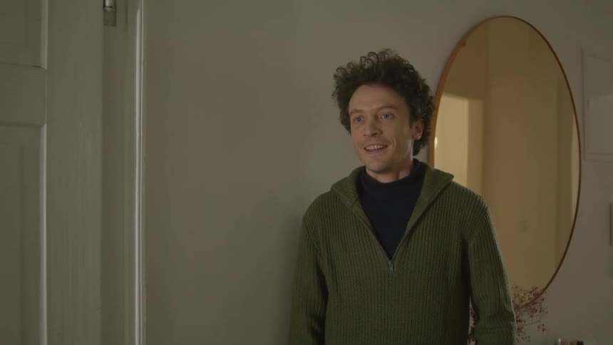 A man in a room hugging a woman with a mirror and a wall in the background