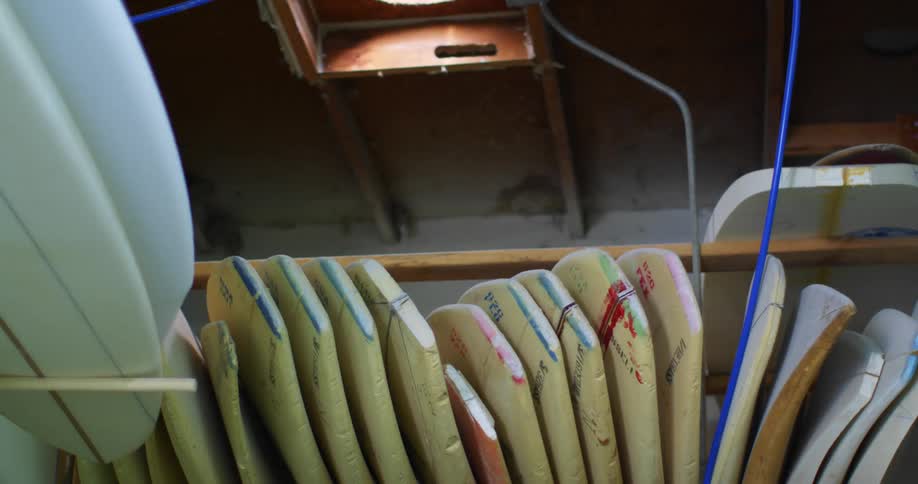 Unfinished surfboards lined up on a shelf inside a workshop