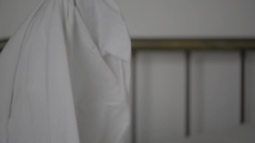 A woman turns her head up and gets up from bed
