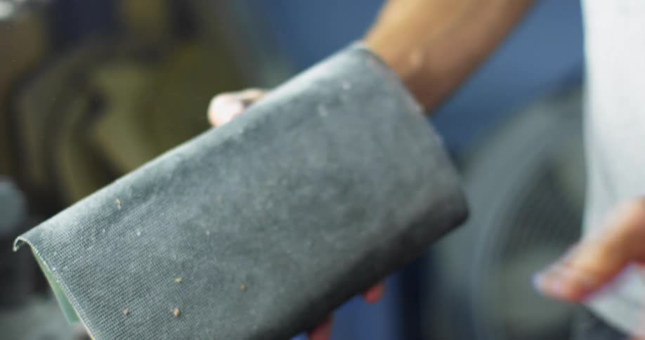 A man walks into his workshop and picks up a sponge filled with sawdust to clean it