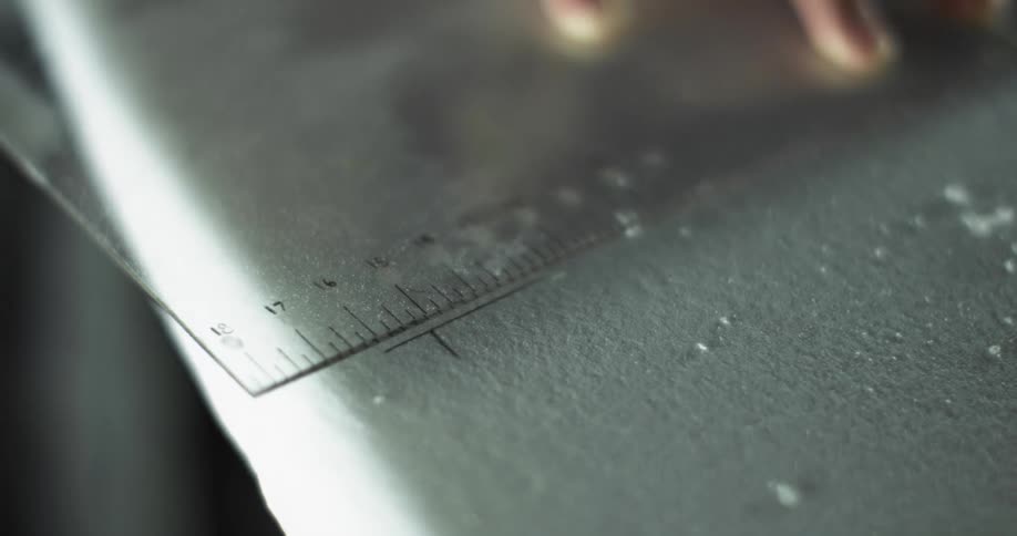 A person marking measurements using a ruler and a pencil