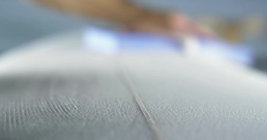 A man places his hand on the surface of a board and then uses a polishing tool to smooth it out