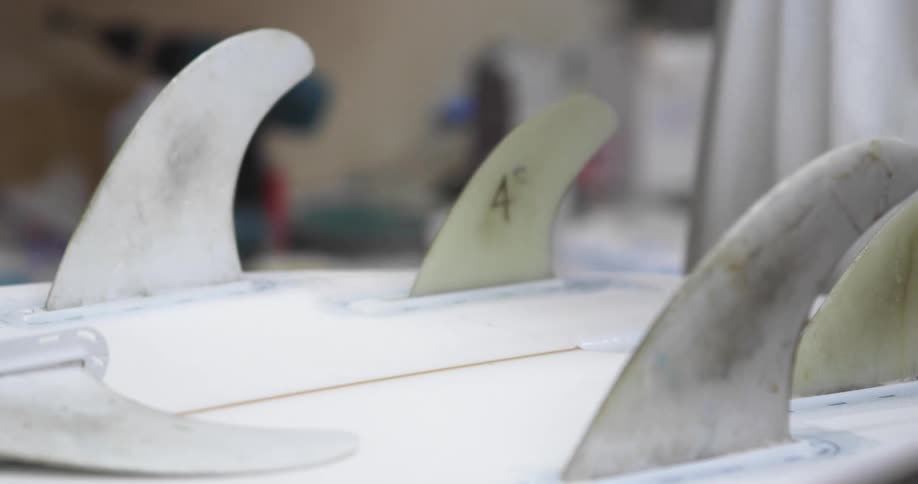 A person with gloves in a room building a surfboard with a wall in the background
