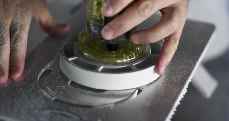 A man uses a power router and guide to cut into foam