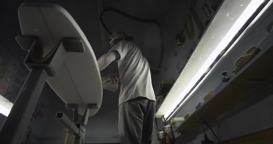 A man working on a surfboard in a shop