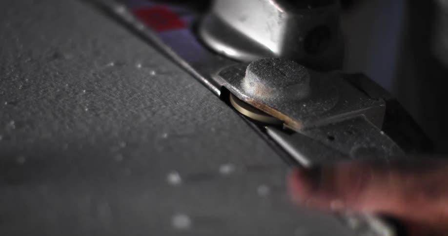A person using a knife to cut a piece of metal