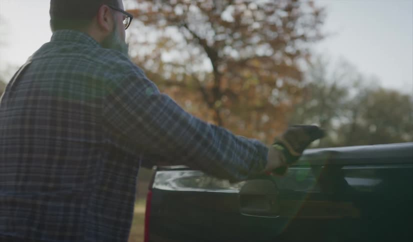 A man closes the back of his truck and his son and him walk to get in the vehicle