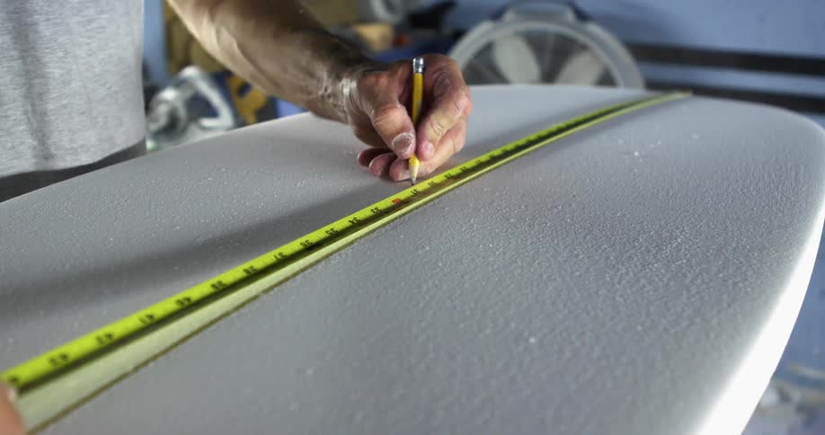 A man that is working on a surfboard in a shop