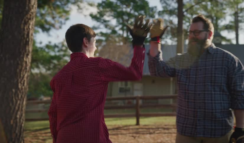 A teenager high fiving his dad after cutting wood with an axe