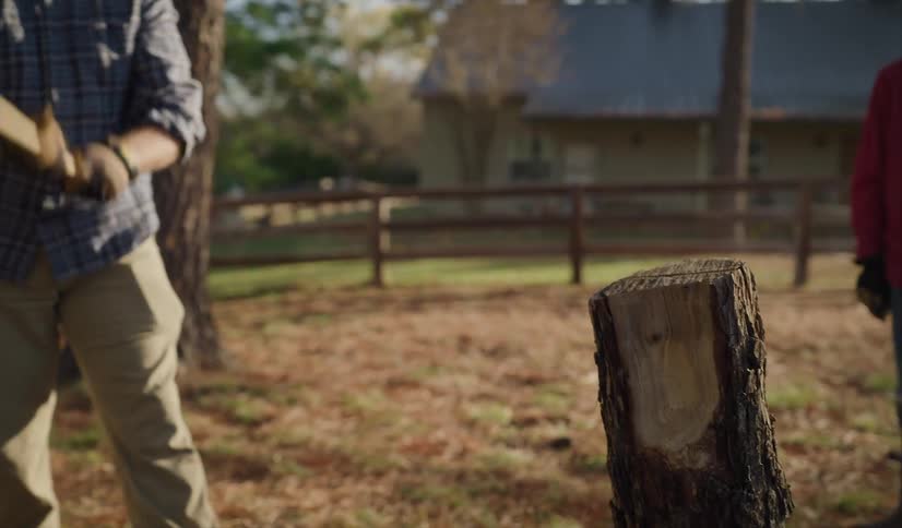 Father shows his son how to cut wood with ax