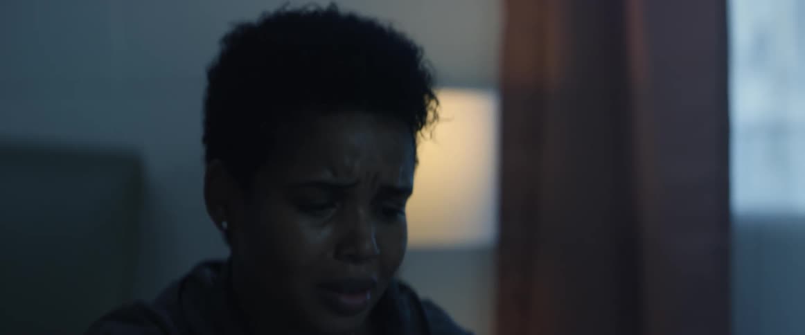 A woman cries and nods her head while seated at a patients hospital bed