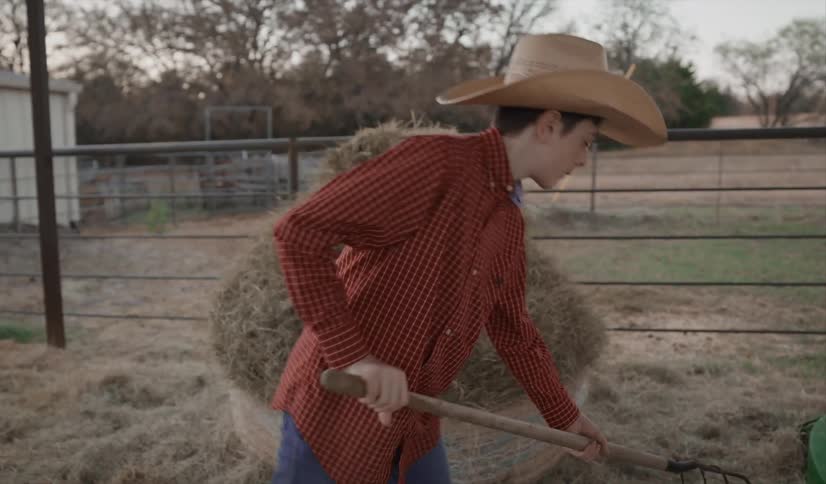 Teenager shoveling hay in a coral at a farm