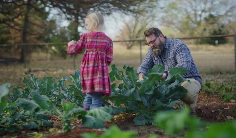 A father and daughter looking at crops in a field