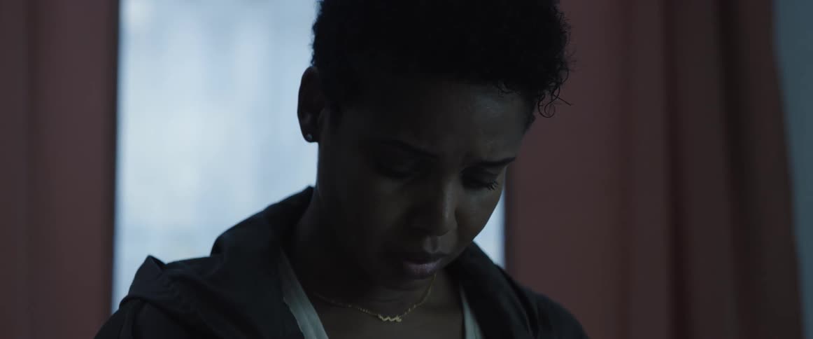 A woman in a room with a necklace with a window and curtains in the background
