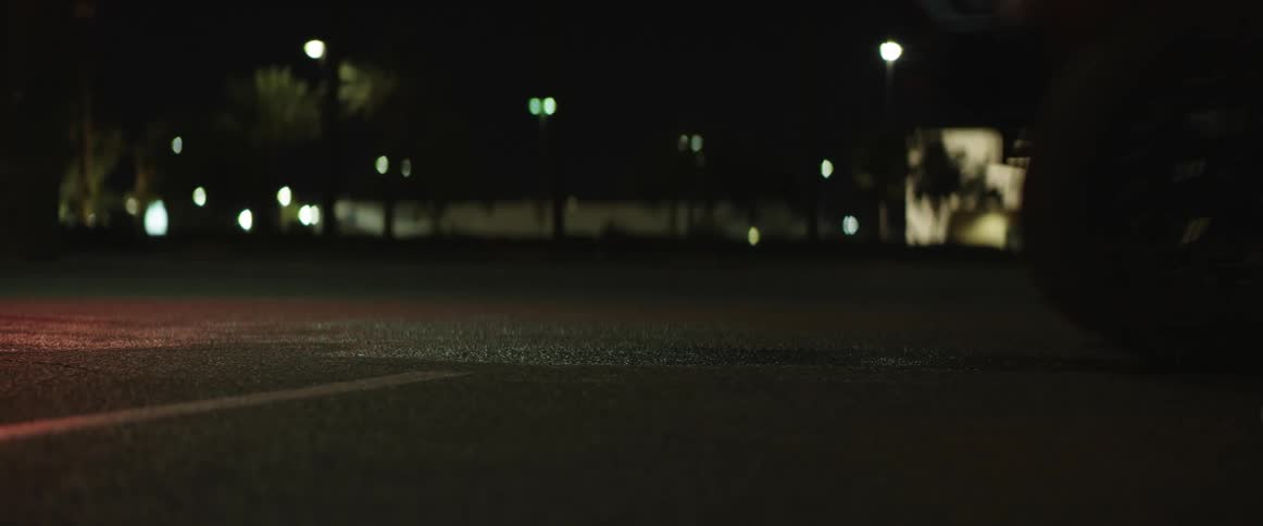 Close up of the asphalt on a city street while a vehicle drives over it at night