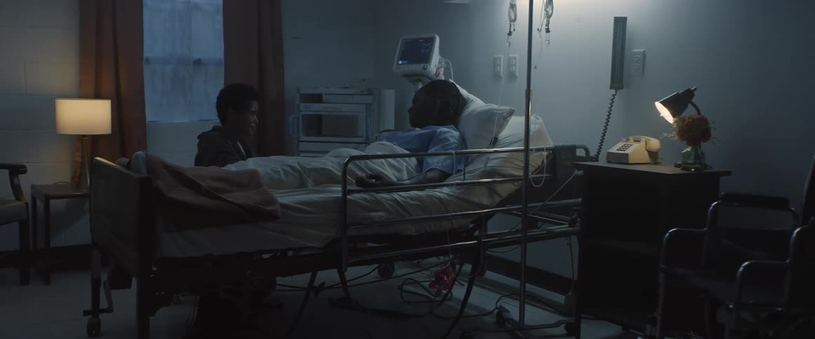 A man chats with his son while lying down in a hospital bed