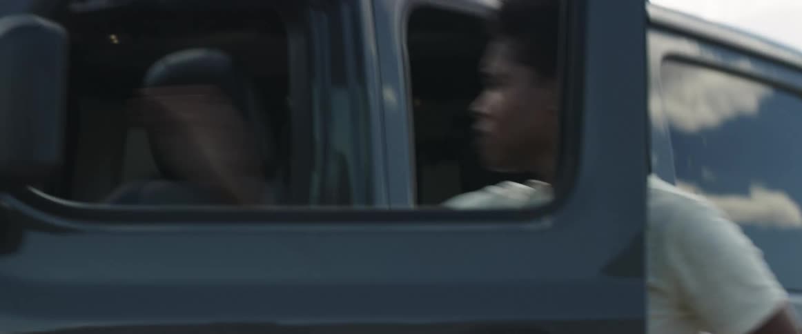 A woman with a smart phone entering into a vehicle with the sky and clouds in the background