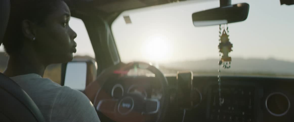 A young man driving a car on a rural area at sunset