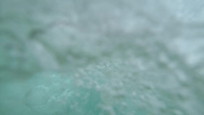 Underwater footage of a wave of clear ocean water crashing overhead