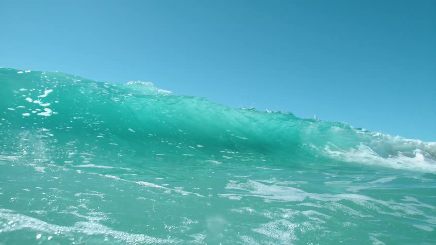 Big blue wave rolls in under a clear blue sky