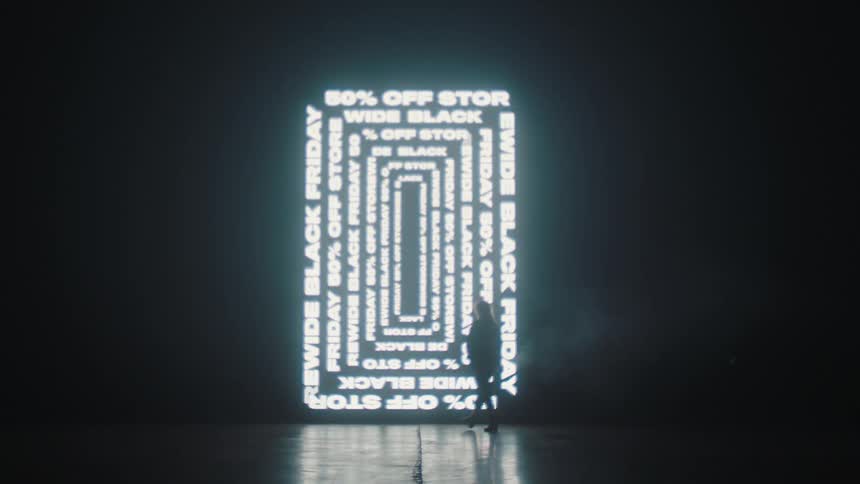 A silhouette of a person walking on a stage with a big screen in the background